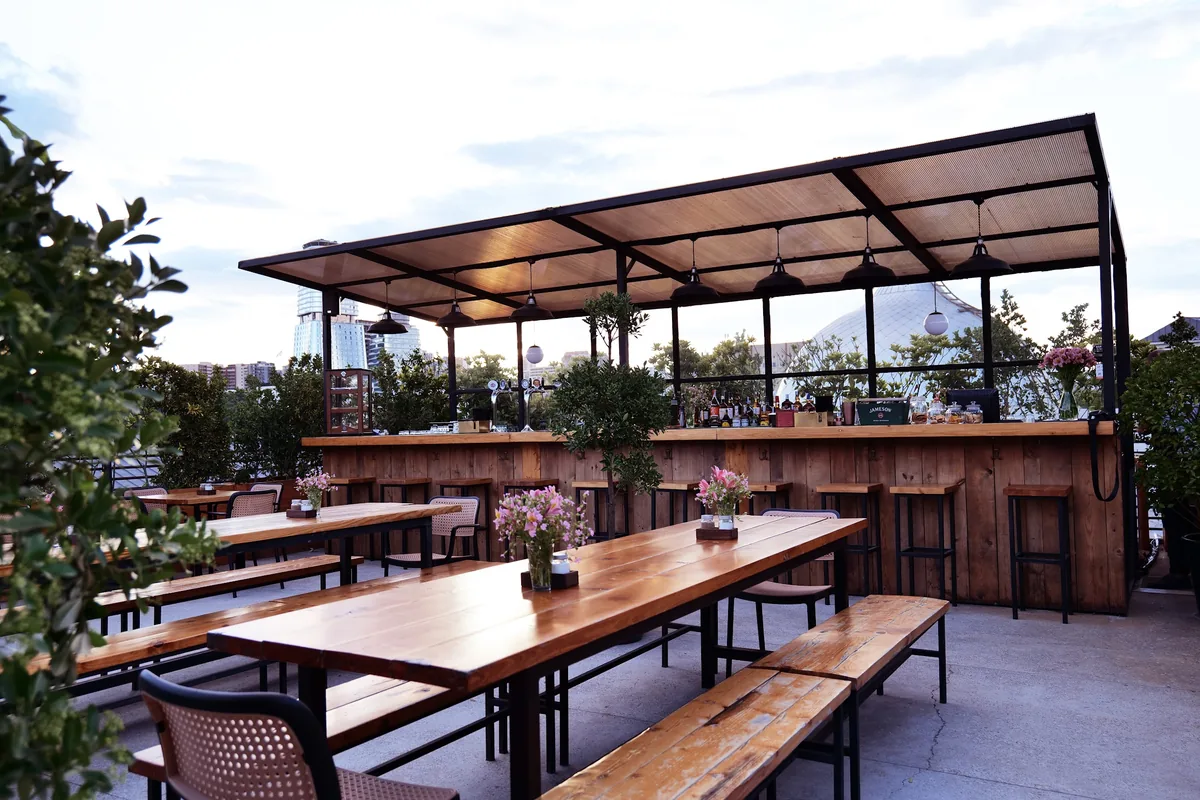 Rooftop terrace with wooden tables and outdoor bar at #8 BBQ HOUSE
