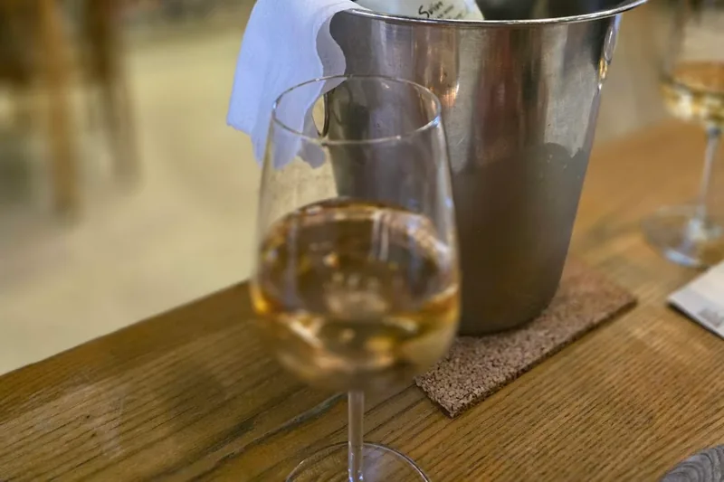 A bottle of white wine in an ice bucket with a glass in the foreground at 8000 Vintages in Vake