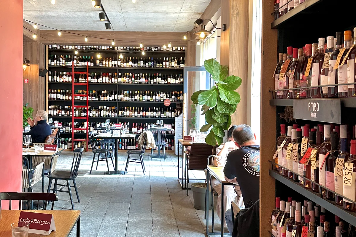 Wine bar seating with floor-to-ceiling bottle racks and a red ladder at 8000 Vintages on Revaz Tabukashvili Street