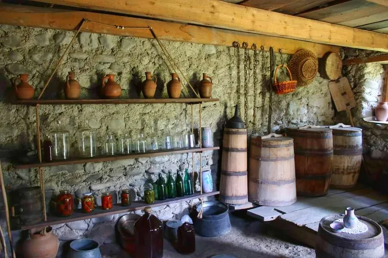 Old stone wine cellar with clay jugs, glass jars and wooden barrels at Akido in Ikalto