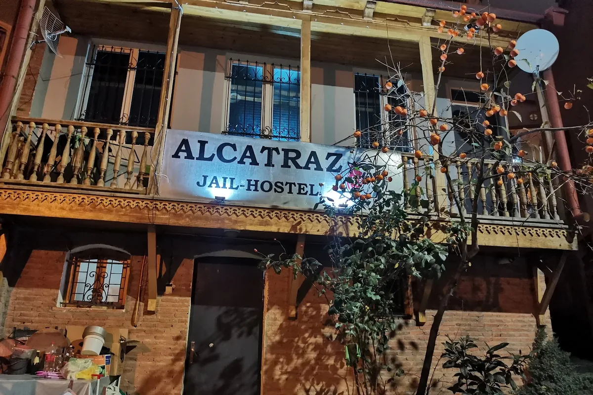 The old wooden-balconied house of Alcatraz Jail-Hostel at night, with its lit Alcatraz sign