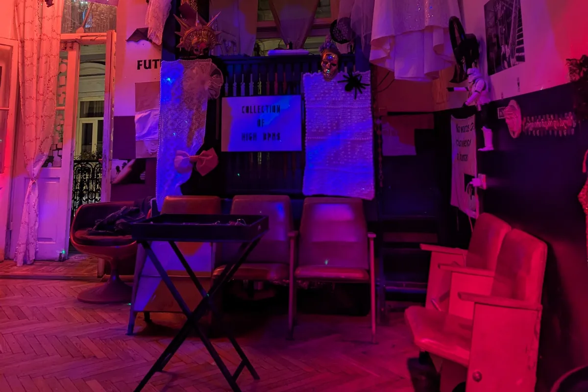 Red-lit room with vintage cinema seats, lace drapes and an open balcony door at Ambavi