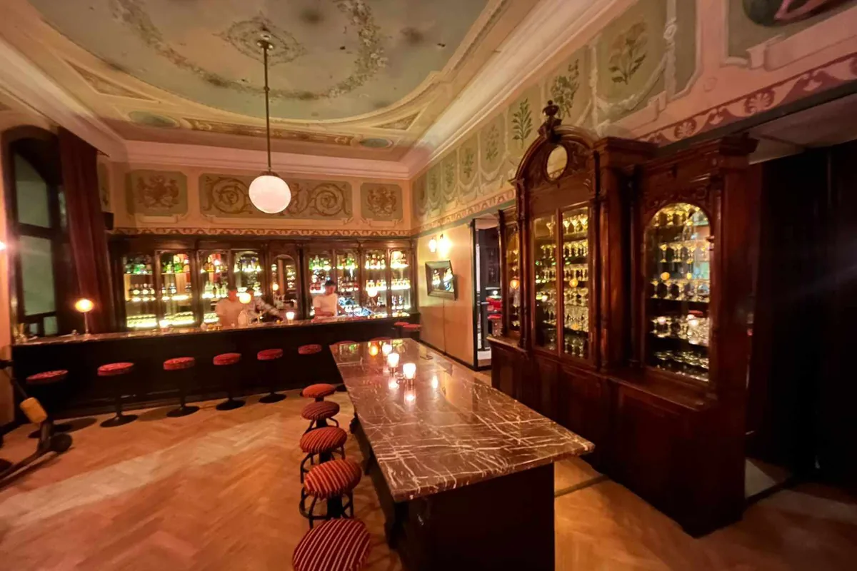 The old pharmacy bar with its painted ceiling and wooden cabinets at Apotheka Bar