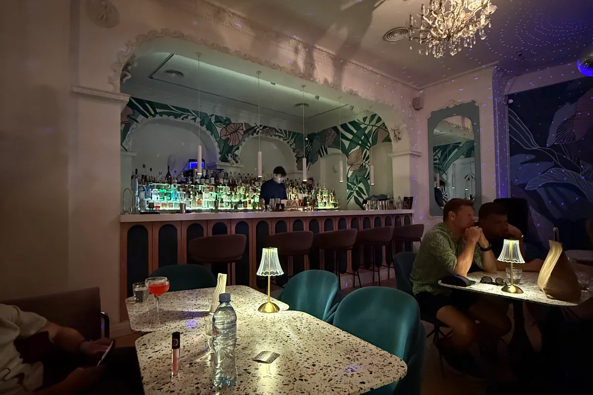 White arches, a tropical mural and a lit back bar over terrazzo tables at Barbar'a Bar on Kote Afkhazi Street