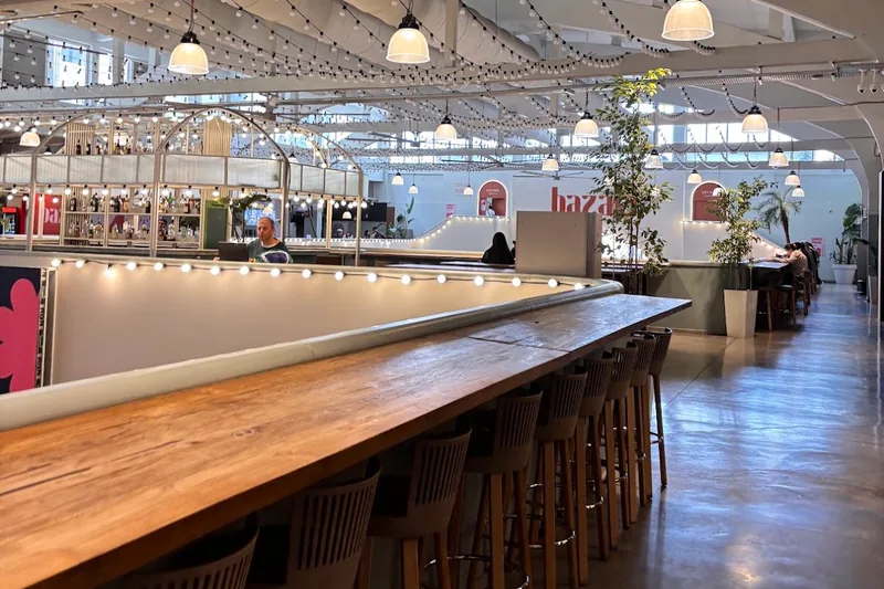Mezzanine bar counter with high stools under string lights at Bazari Orbeliani