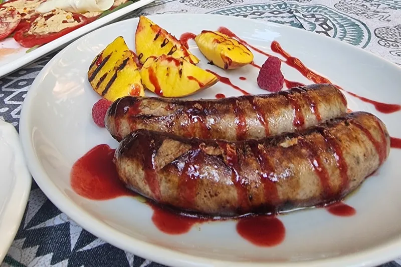Grilled sausages with sauce and peaches at Beletage Restaurant