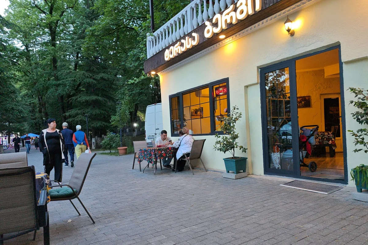 The yellow facade and sidewalk tables of Bergi under its balcony terrace in central Borjomi