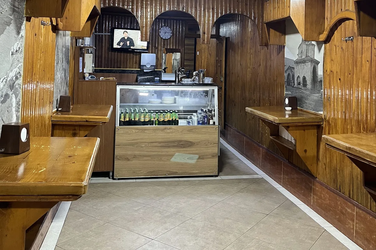 The wood-paneled room at Bikentia's Kebabery in Kutaisi, with standing ledges along the walls and a drinks counter at the back