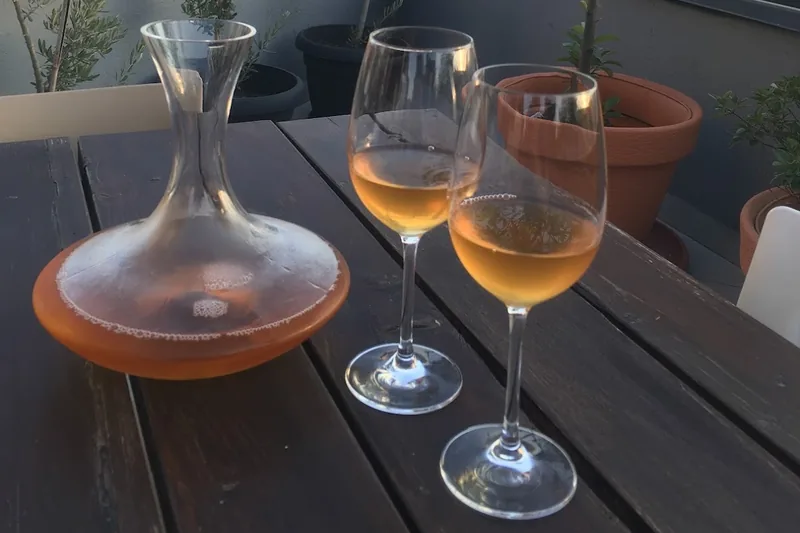 Decanter and glasses of amber wine on a rooftop table at Bina N37