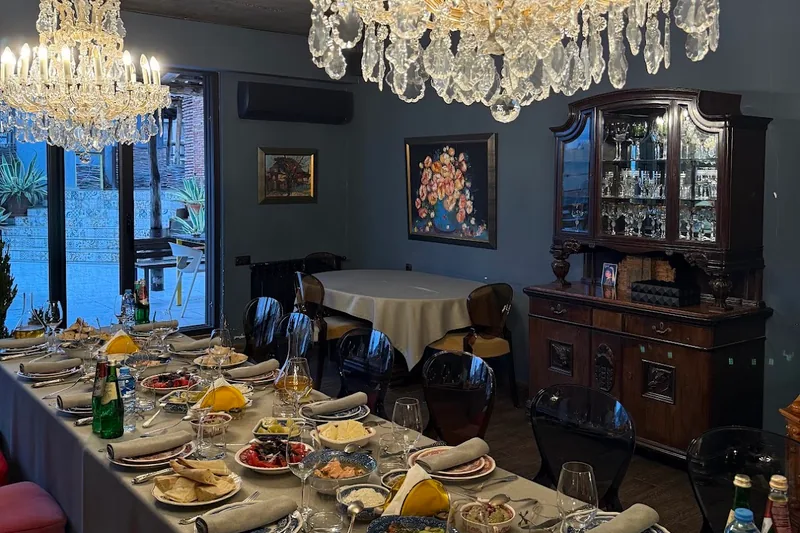 Dining room with ornate crystal chandelier and long set table at Bina N37