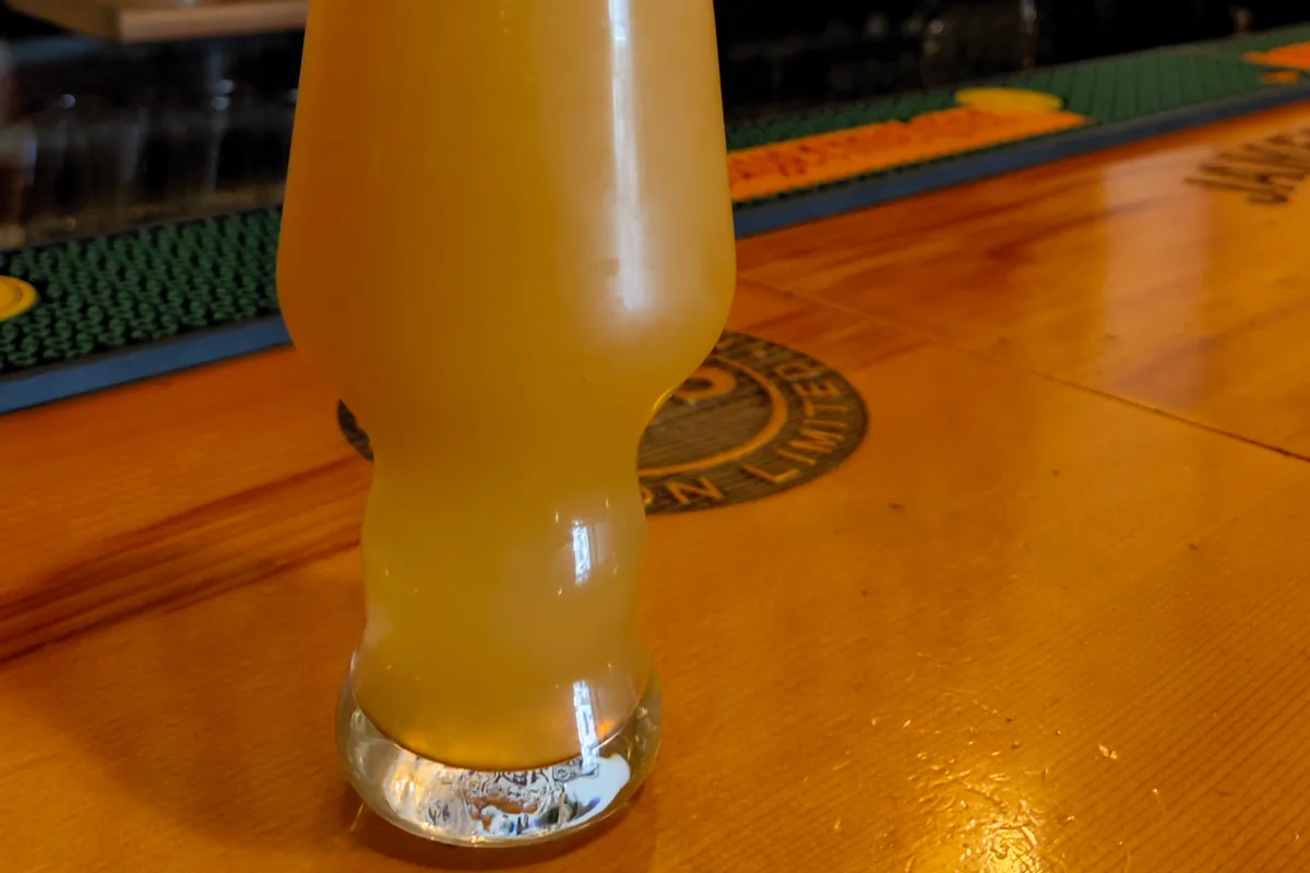 Glass of hazy beer on a wooden bar counter at Black Dog Bar