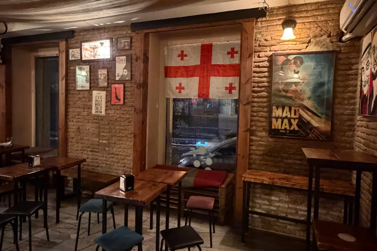 Bar seating area with exposed brick walls and posters at Black Dog Bar