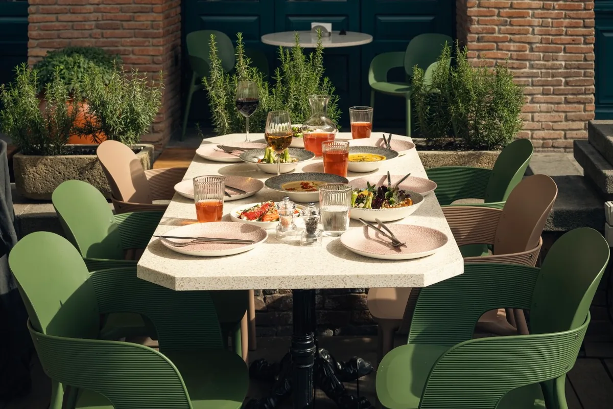 Outdoor patio dining table with green chairs at Cafe Daphna Meidan