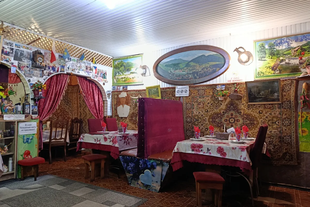 Carpet-hung walls, painted landscapes and tables set for lunch in the dining room of Cafe Tourist in Borjomi