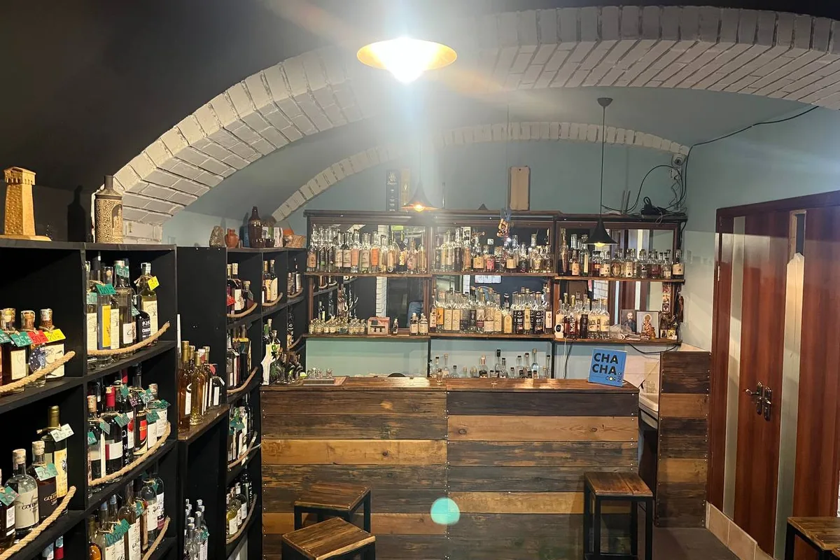 Bar and shelves of chacha bottles under a vaulted ceiling at Chacha Corner
