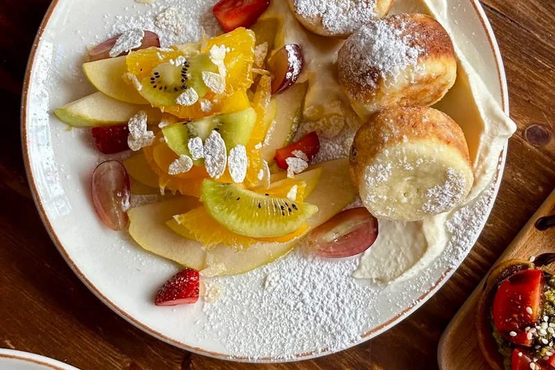 Syrniki with sliced fresh fruit and cream at Chaduna