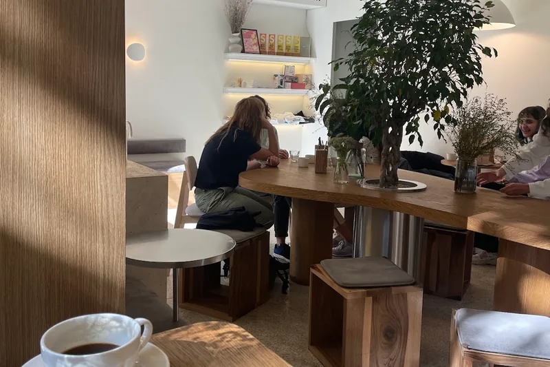Cafe interior with wooden communal table and indoor plant at Chakandrila Cooking Classes