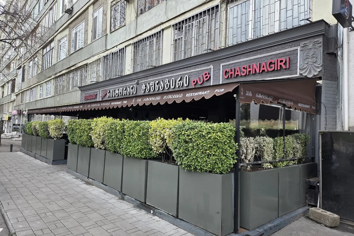 The hedge-lined front terrace under the restaurant and pub signs at Chashnagiri on Vazha-Pshavela Avenue