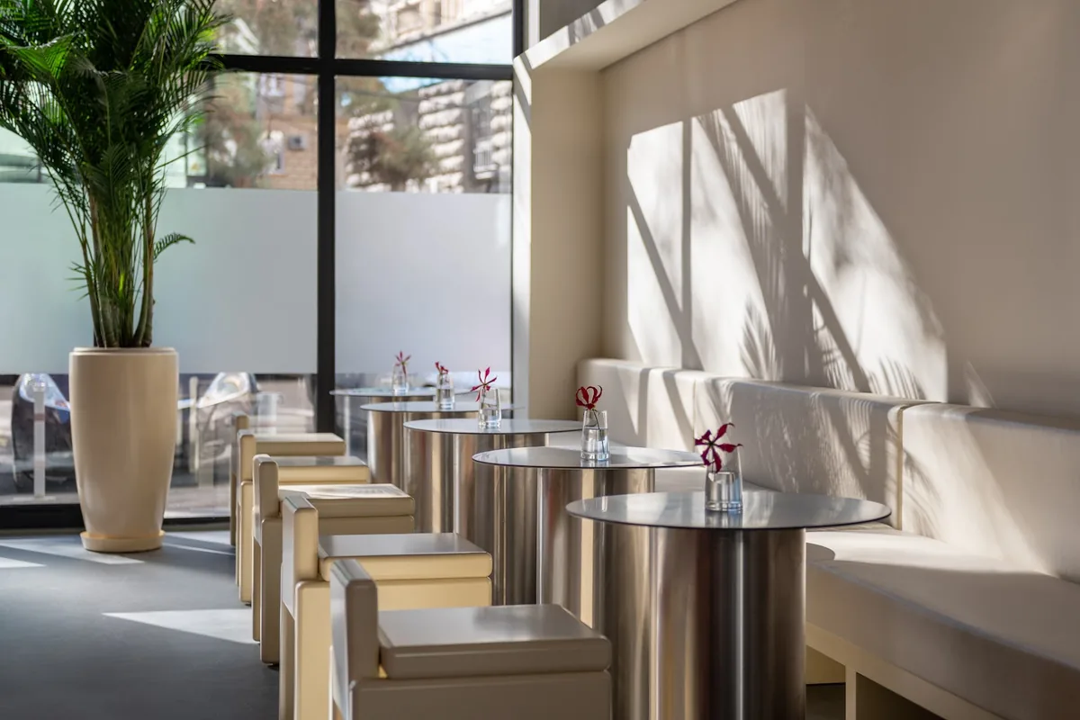 Steel tables and a cream banquette by the big street window at Chicos in Vake