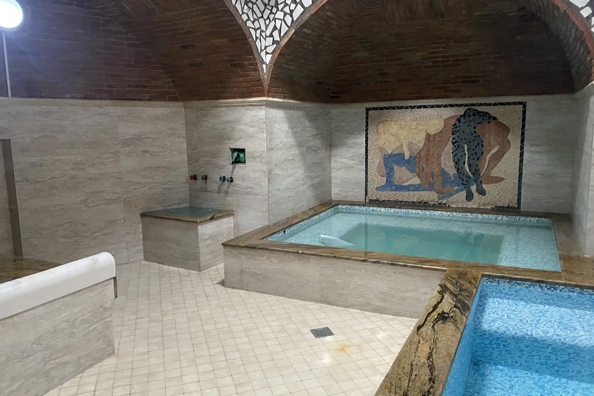Private room with a tiled sulfur pool and a painted mural at Chreli Abano