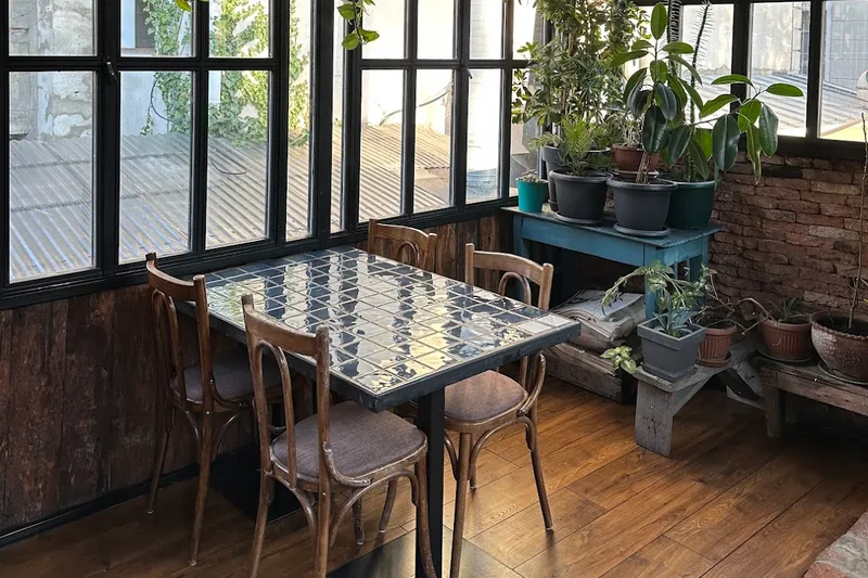 Enclosed veranda with tiled tables and hanging plants at Chveni