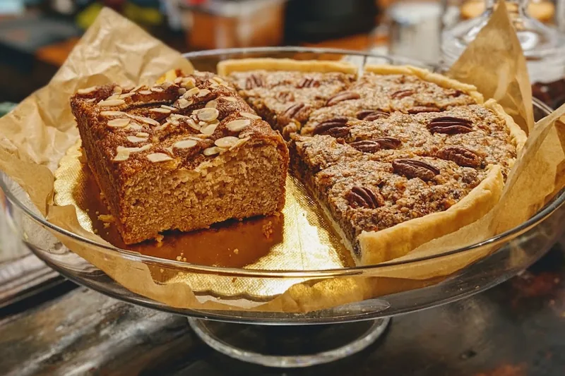 Almond cake and a pecan tart on a glass cake stand at Coffee Place