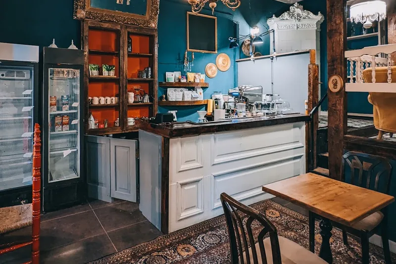 Teal-walled cafe room with a white counter and an ornate ceiling at Coffee Place