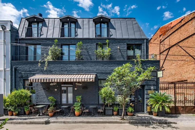 The dark brick facade and street terrace of Communal Plekhanovi on Ninoshvili Street