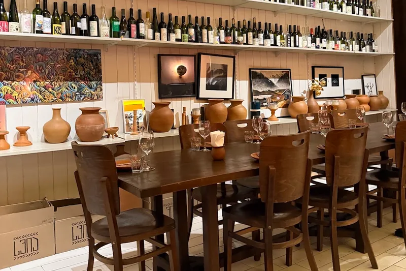 Wooden dining table and a wall lined with wine bottles at Craft Wine Restaurant