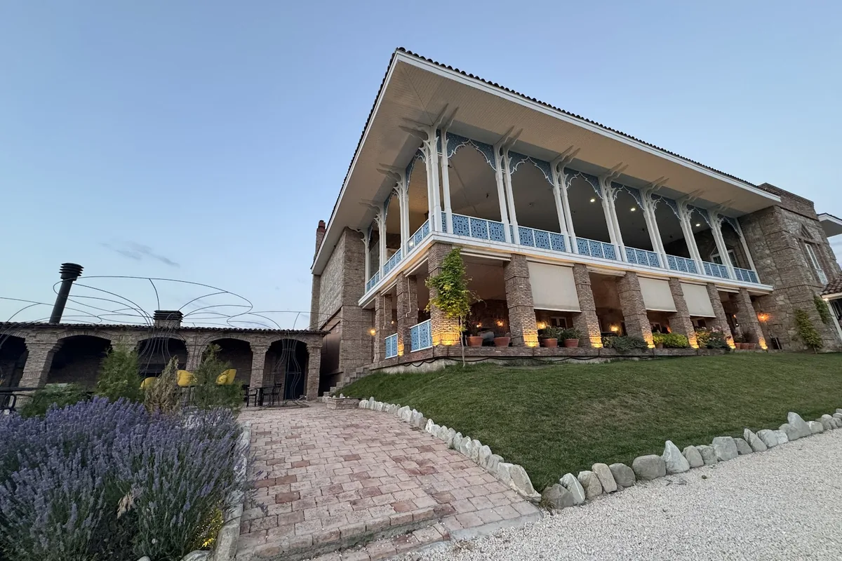 The stone and brick building with its long carved veranda above a lawn at Dergi near Sighnaghi