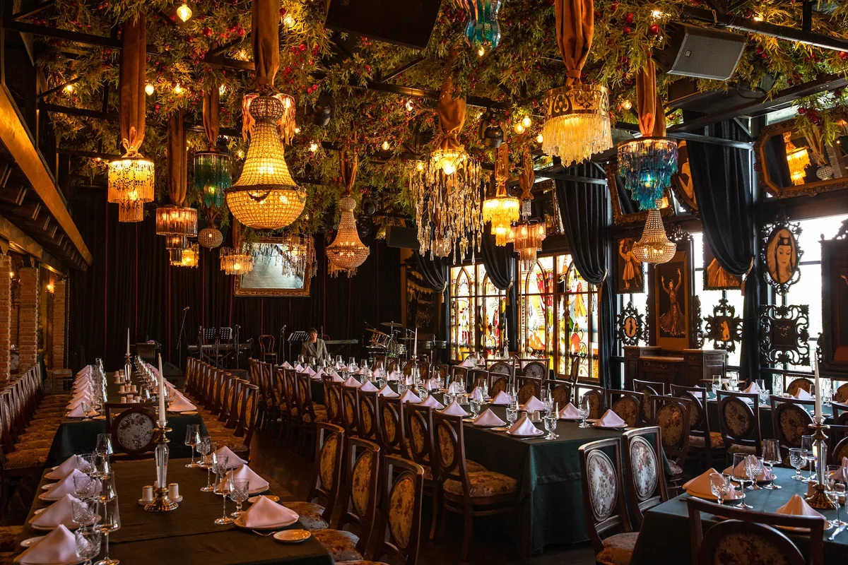 Opulent dining hall with chandeliers and set banquet tables at Ethnographer restaurant