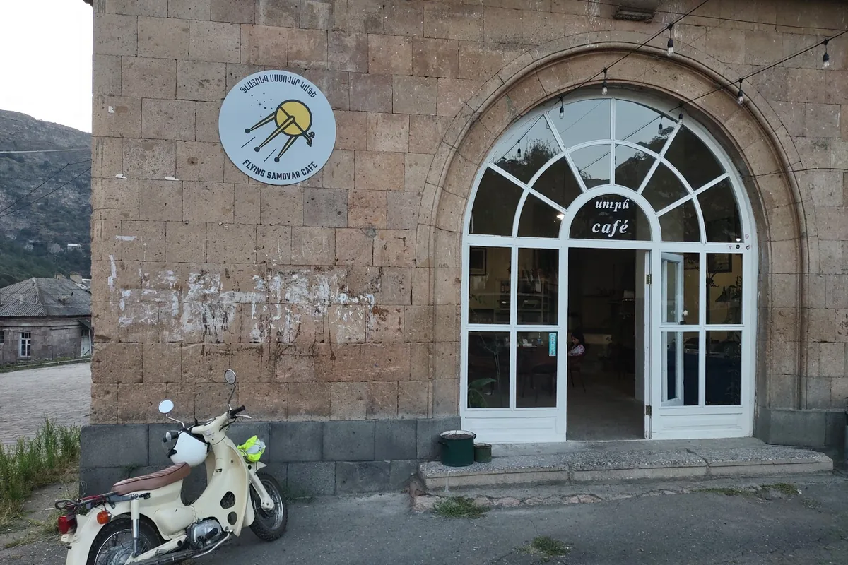 The arched stone facade and sign of the Flying Samovar Cafe in Tumanyan