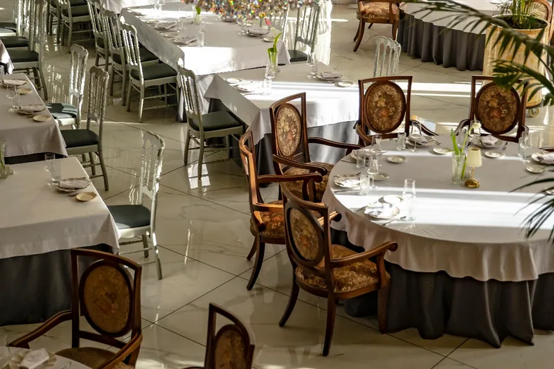 The dining hall at Georgian House, round tables dressed in white with carved wooden chairs
