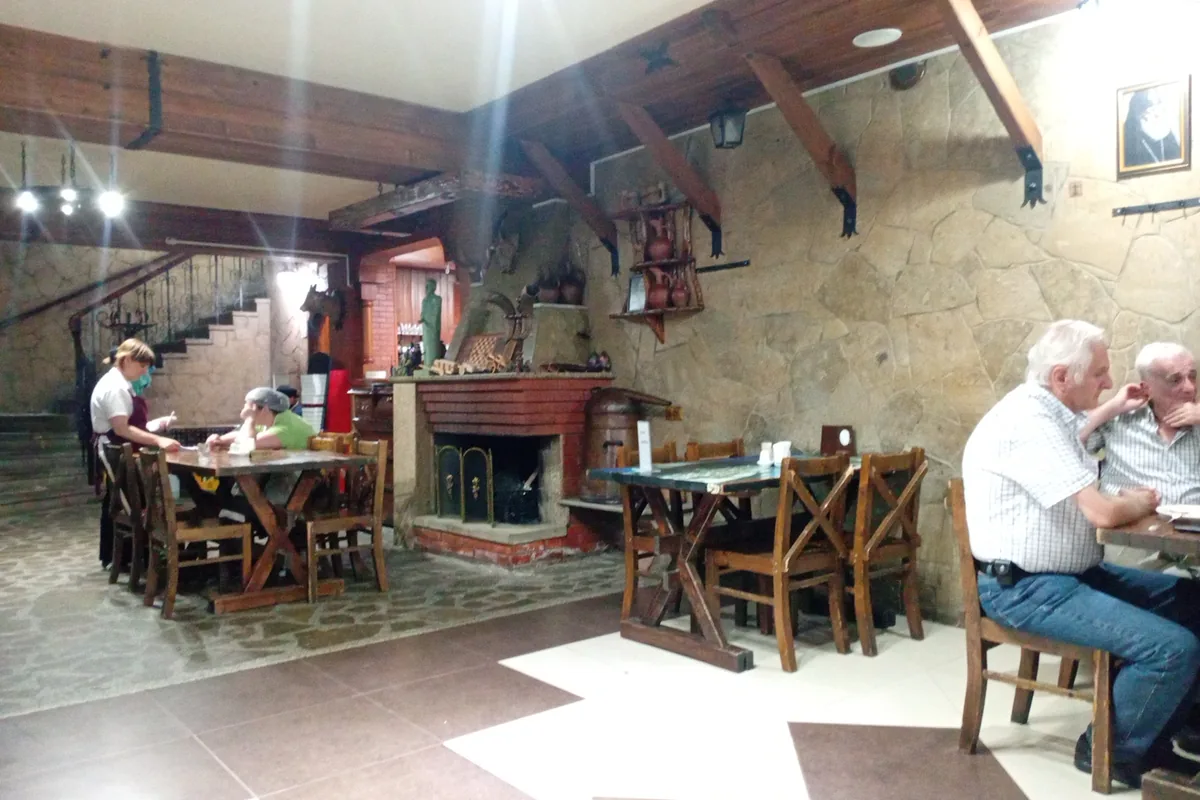 Dining room with a fireplace and wooden tables at Ghebi