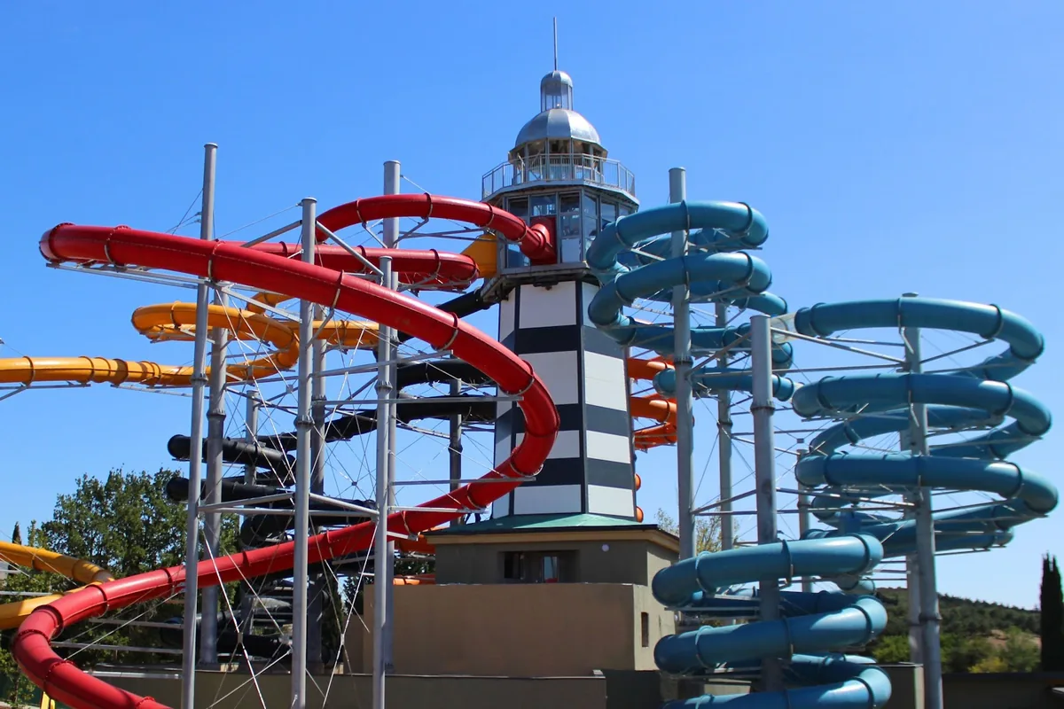 Red, blue and yellow water slides wrapped around the lighthouse tower at Gino Paradise water park