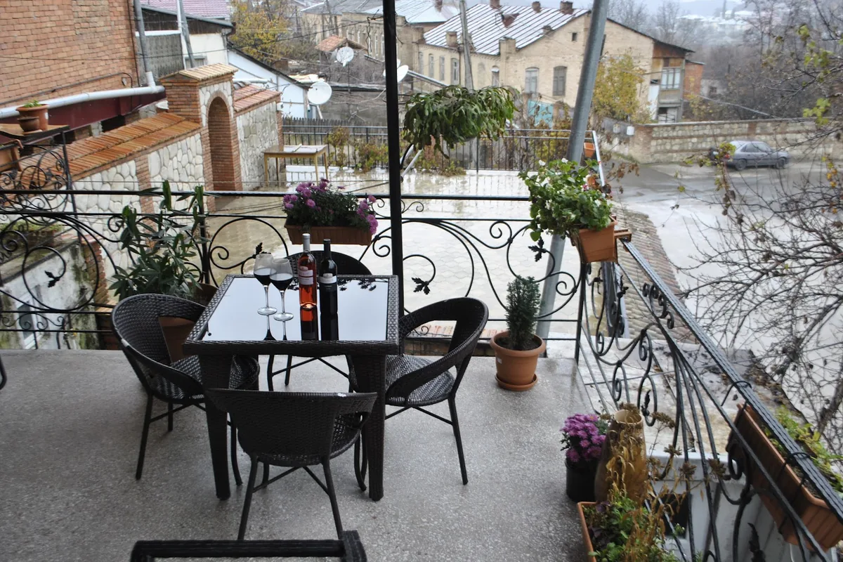 Balcony with a wicker table set and iron railings over the street at Guest House Eka & Gio in Sighnaghi