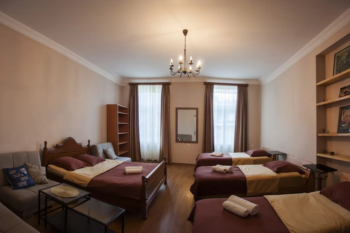 High-ceilinged guest room with a chandelier and several beds at Guest House Lile in Sololaki
