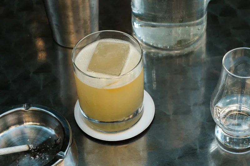 Yellow cocktail over a clear ice block in a rocks glass at G.U.M