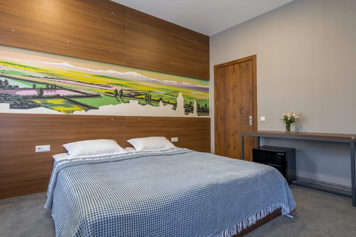 Double room with a painted Alazani Valley mural above the bed at Hotel History in Sighnaghi
