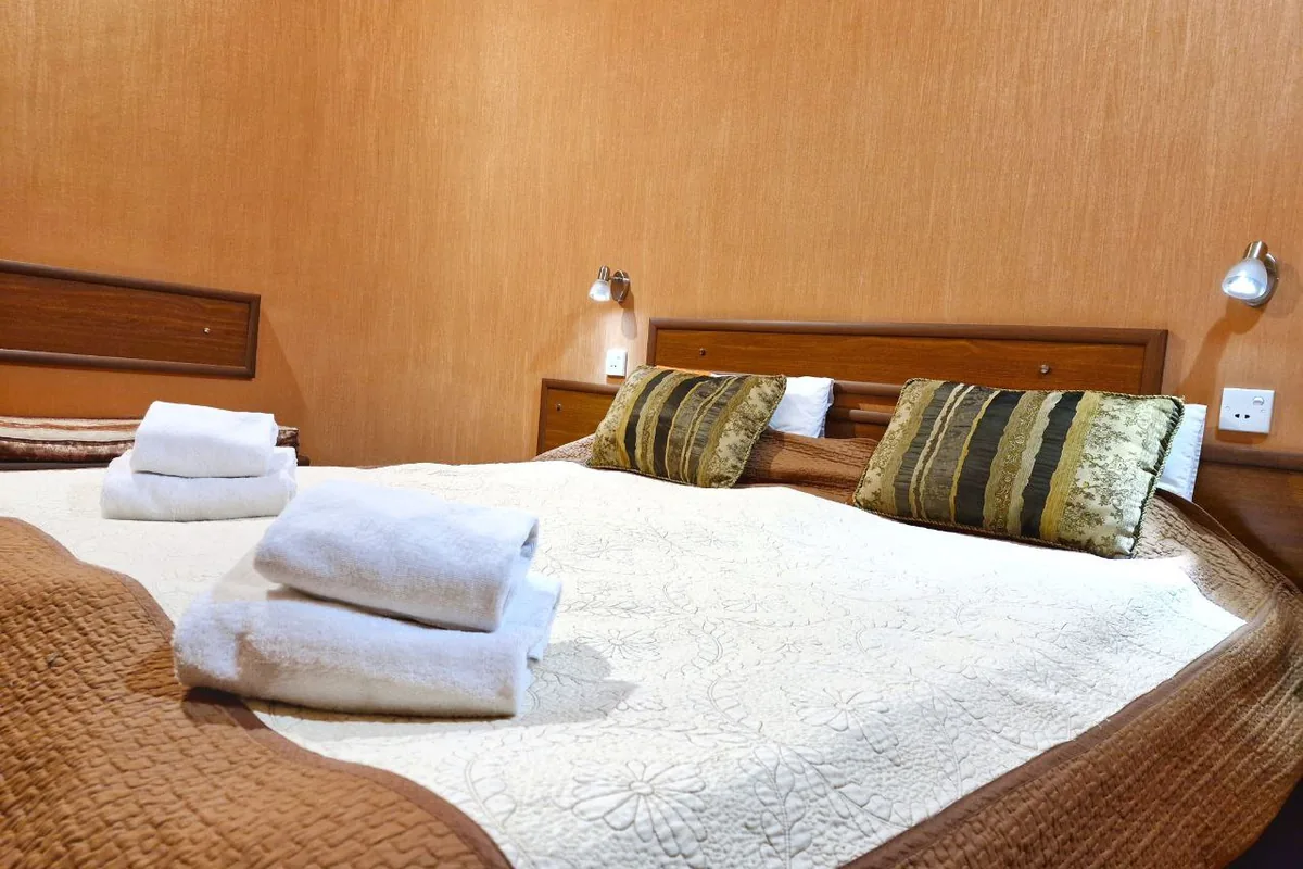Double bed with folded towels and striped cushions in a guest room at Hotel Pavo