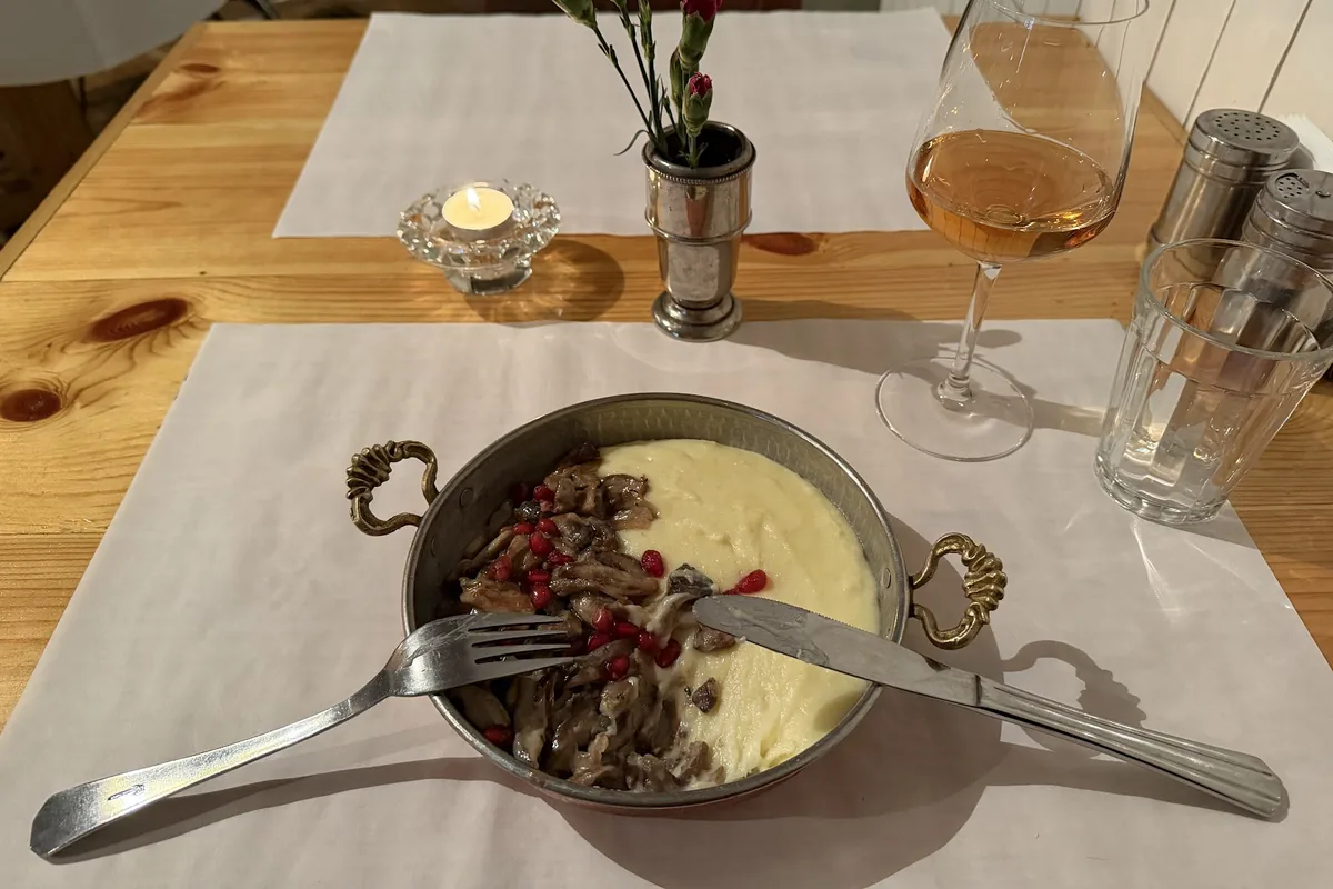 Oyster mushrooms with pomegranate seeds and mashed potato in a copper pan at Iasamani