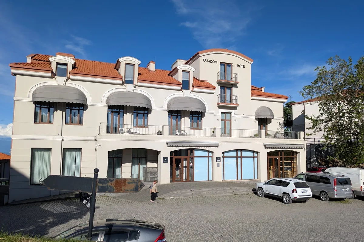 The cream facade with awnings and a tiled roof of the Kabadoni hotel in Sighnaghi