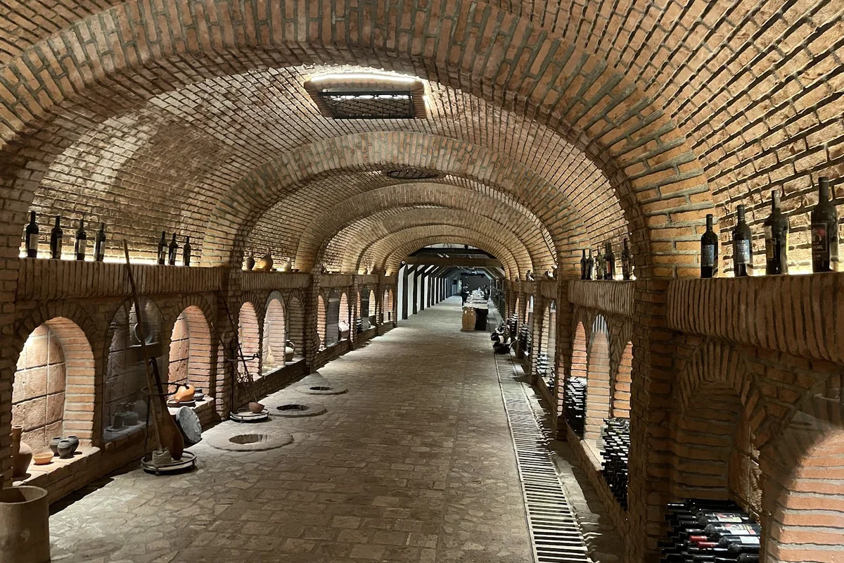 The brick-vaulted wine tunnel at Khareba's Kvareli Wine Cave, lined with wine bottles and clay jars