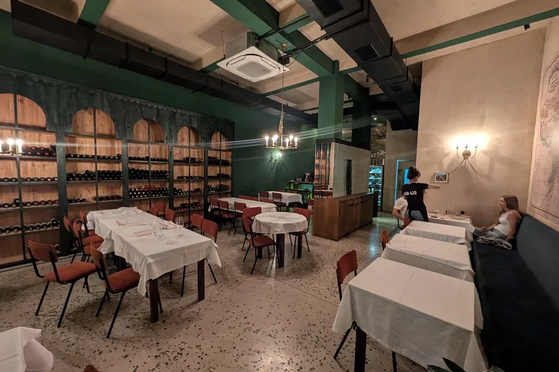 Dining room with green walls, wine shelves and white tablecloths at Khash-Khash on Mazniashvili Street