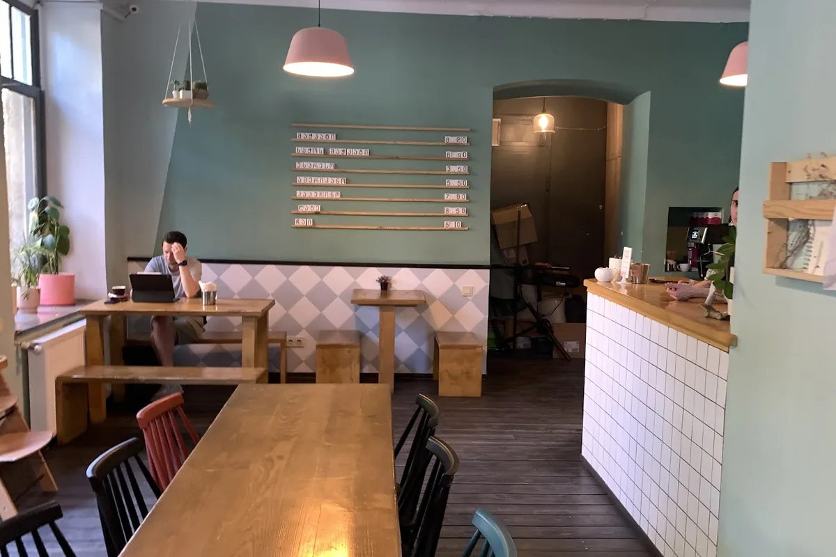Wooden tables, a tiled counter and mint-green walls at Kikliko, a breakfast cafe in Vake