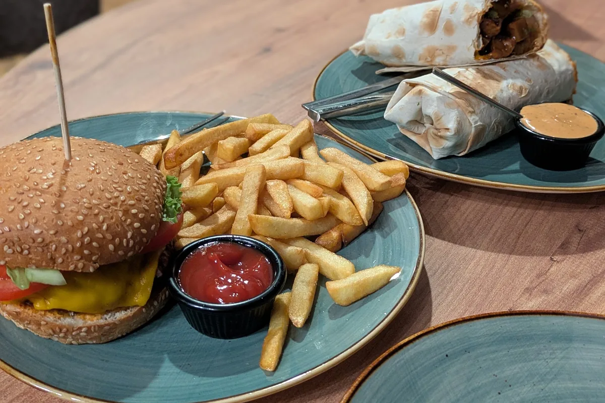 Vegan burger with fries and wraps on green plates at Kiwi Vegan Cafe