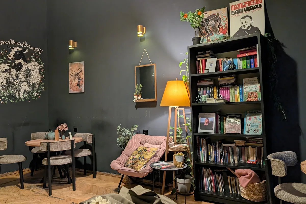 Seating area with bookshelf and armchair at Kiwi Vegan Cafe