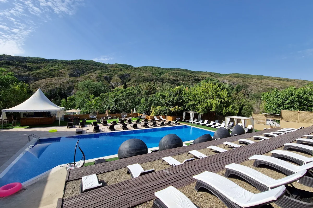 Outdoor pool with sun loungers and hill views at Krtsanisi Residence