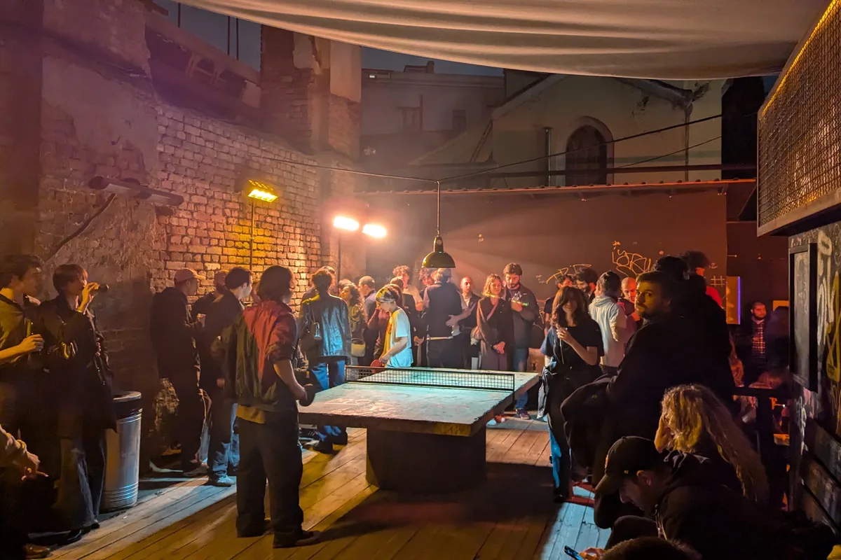 Outdoor courtyard with ping pong table and crowd at Left Bank