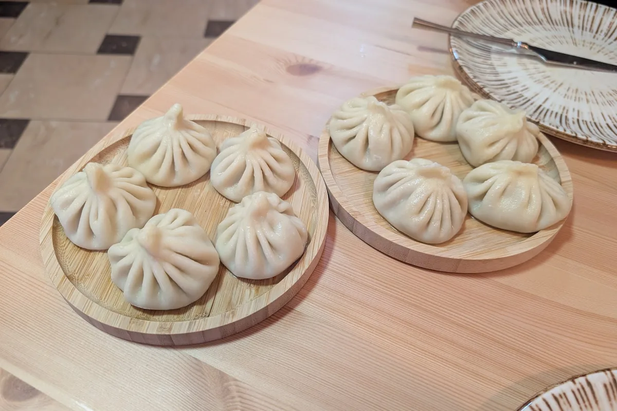 Two wooden boards of khinkali on a pale wooden table at Leila's Khinkali on Shevchenko Street, Tbilisi